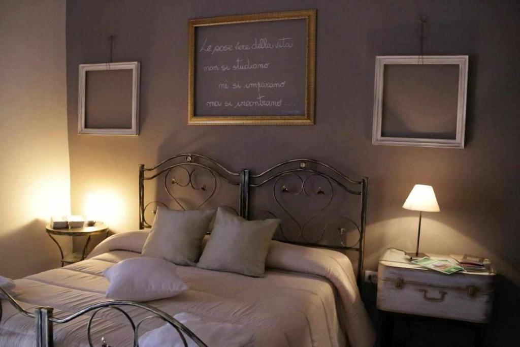 um quarto com uma cama com um quadro negro na parede em Le Dimore degli Artisti em Venosa
