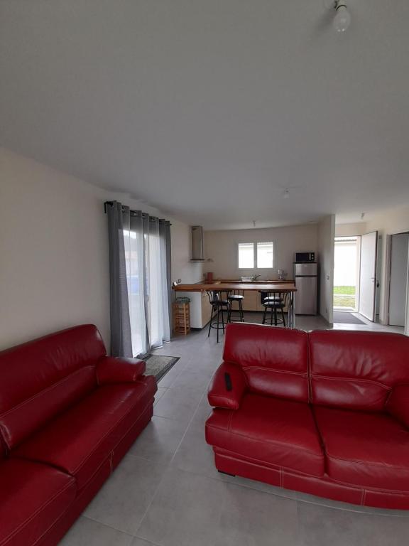 sala de estar con sofá rojo y cocina en Maison Aureilhan Mimizan Landes, en Aureilhan