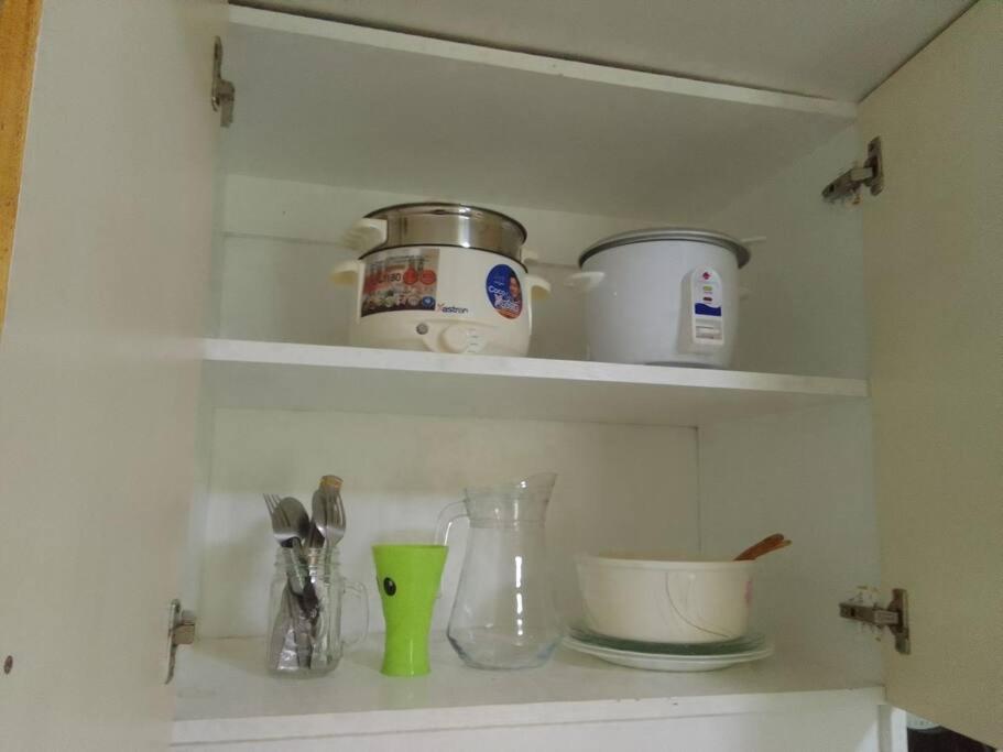 a kitchen counter with bowls and utensils on a shelf at Studio for Rent near Ortigas Extension in Cainta