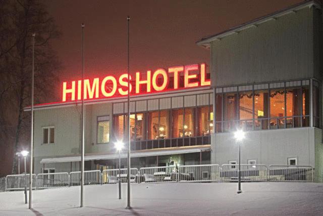 a hmos hotel building with a neon sign at night at Hotel Himos in Jämsä