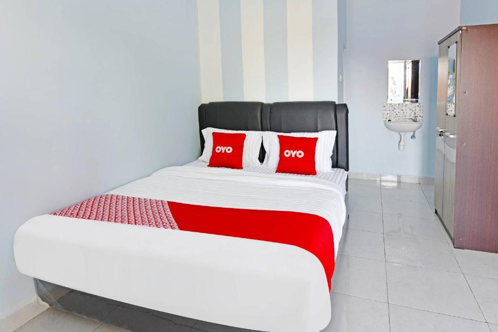 OYO Life 91399 Homestay Trendy Syariah في سيلاكاب: سرير كبير مع وسائد حمراء في الغرفة