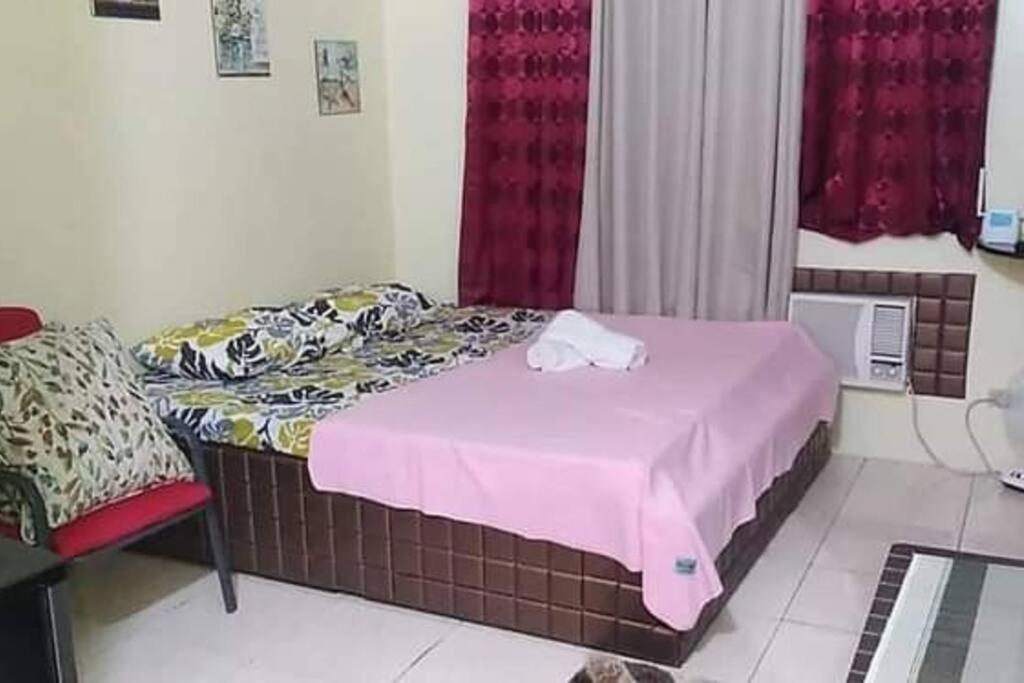 a small bedroom with a bed with a pink blanket at Aliyahs’s Place: Staycation in Valley Golf Cainta in Cainta