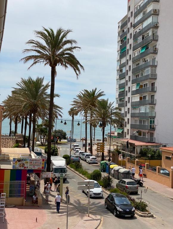 a city street with palm trees and a tall building at Las Palmeras in Benalmádena
