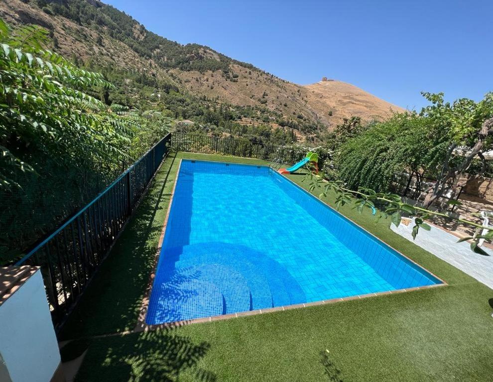 a large blue swimming pool in front of a mountain at Casa Rural La Fabrica De Nacelrio in Cazorla