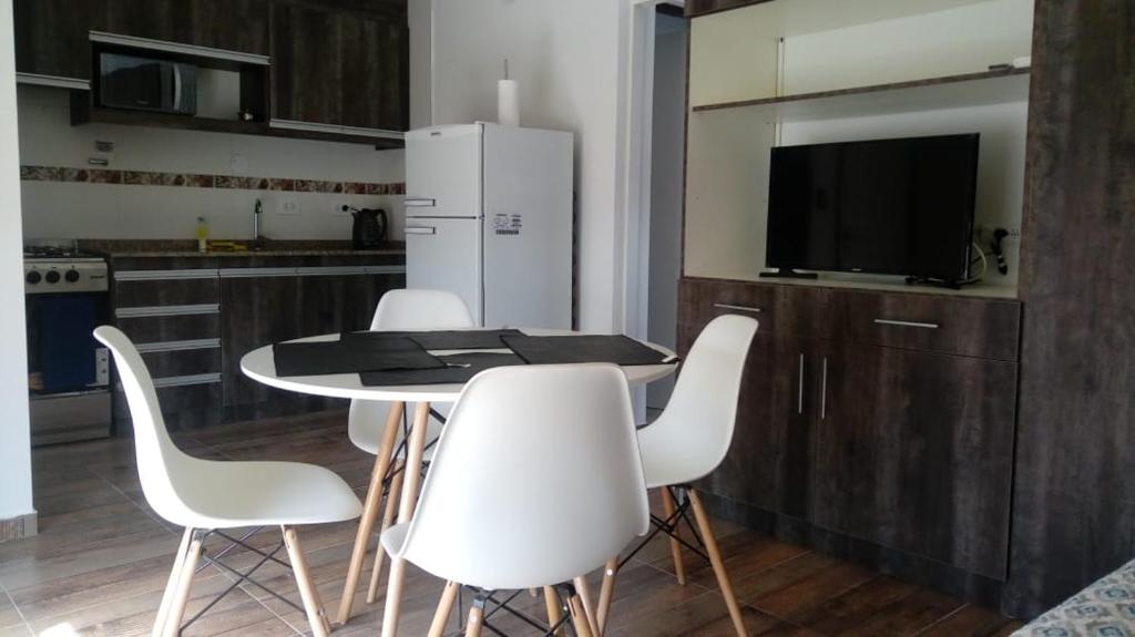 a kitchen with a table with white chairs and a refrigerator at Abril Dptos Temporarios in San Juan