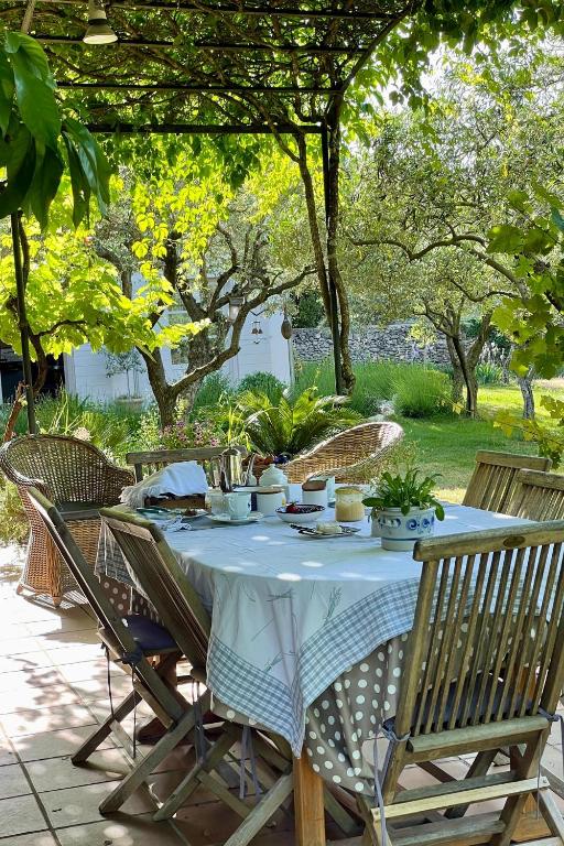 a table with a white table cloth and chairs and trees at la maison des Olivettes in Uzès