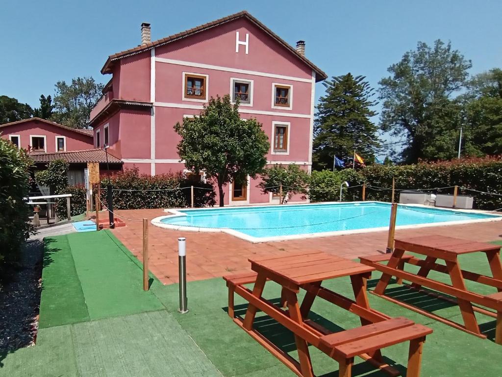 a house with a swimming pool and two picnic tables at Hotel Casa Vitorio in Cudillero