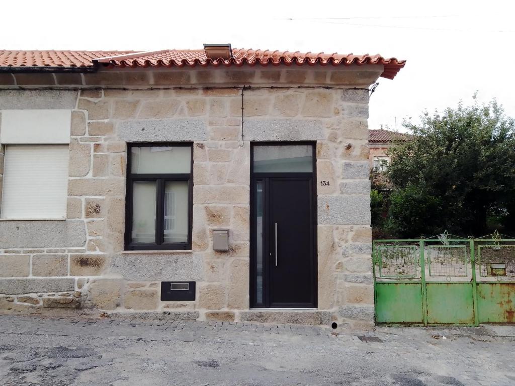 una casa de piedra con una puerta negra y dos ventanas en Casa da Florbela, en Fafe