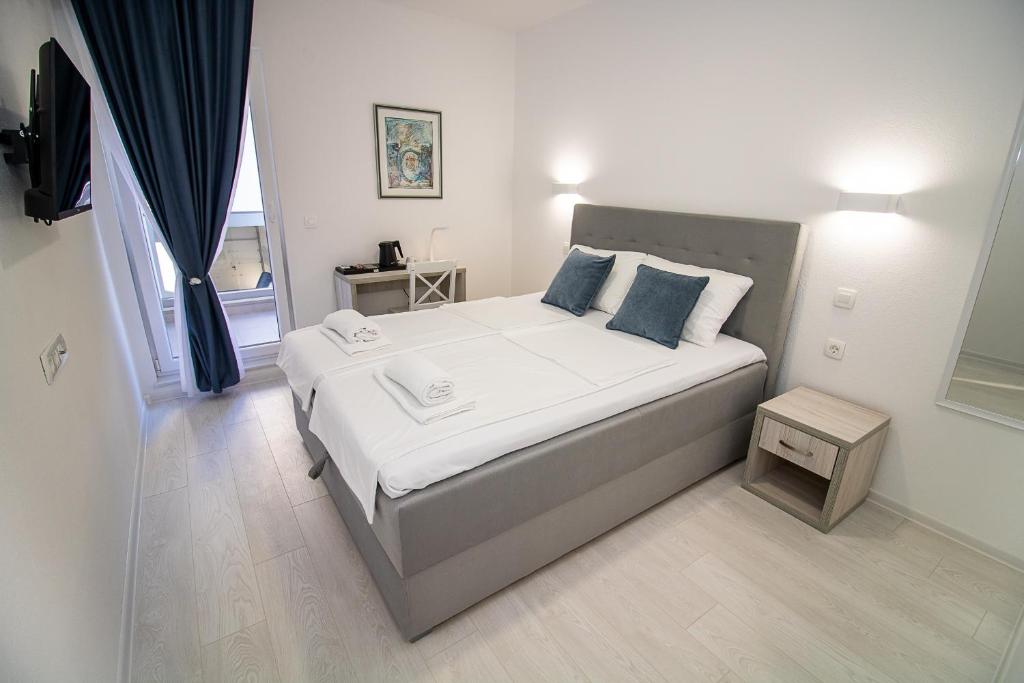 1 dormitorio con 1 cama con sábanas blancas y almohadas azules en Villa Sonata, en Mostar