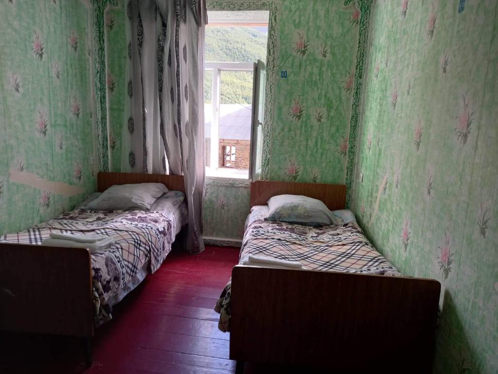 two beds in a room with a window at Guesthouse ZAMO in Ushguli
