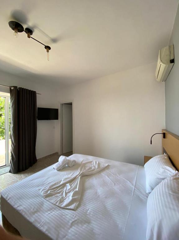 a large white bed in a bedroom with a window at Seafront Rooms - Private Beach Access in Sarandë