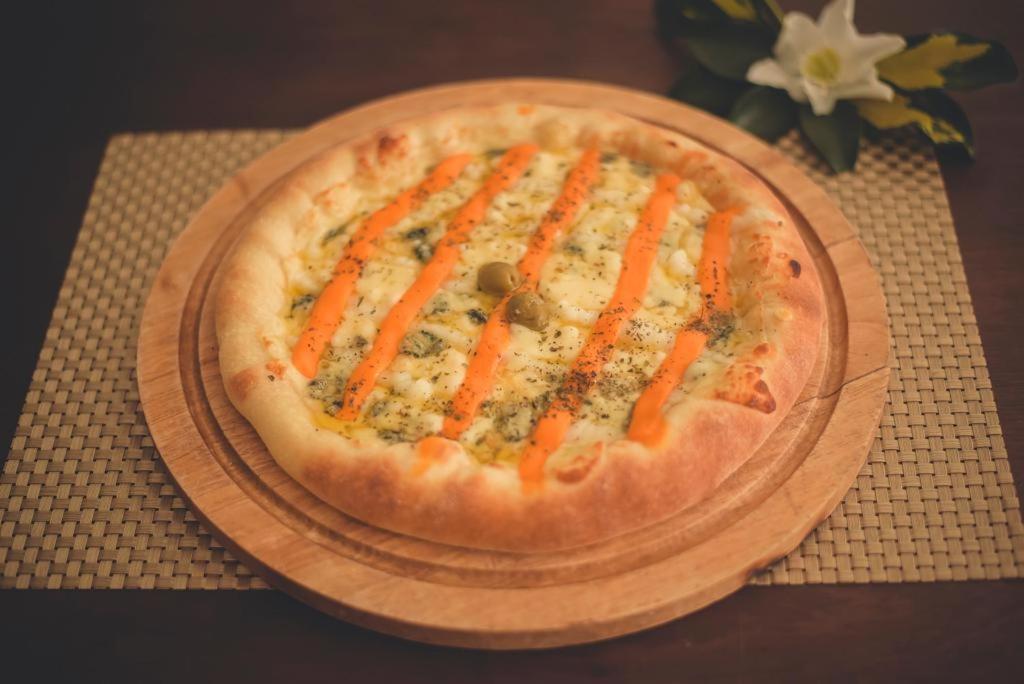 una pizza en un plato de madera en una mesa en Hotel Kika, en São Gabriel