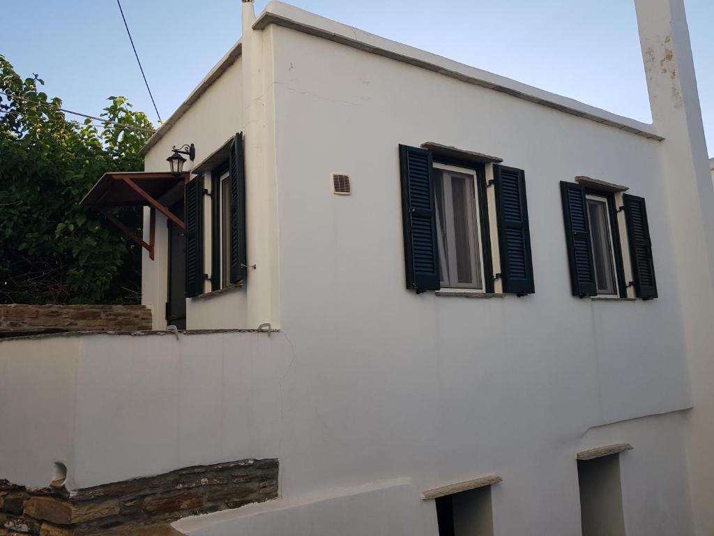 a white building with black shuttered windows at GUEST HOUSE KALLIOPI in Kómi