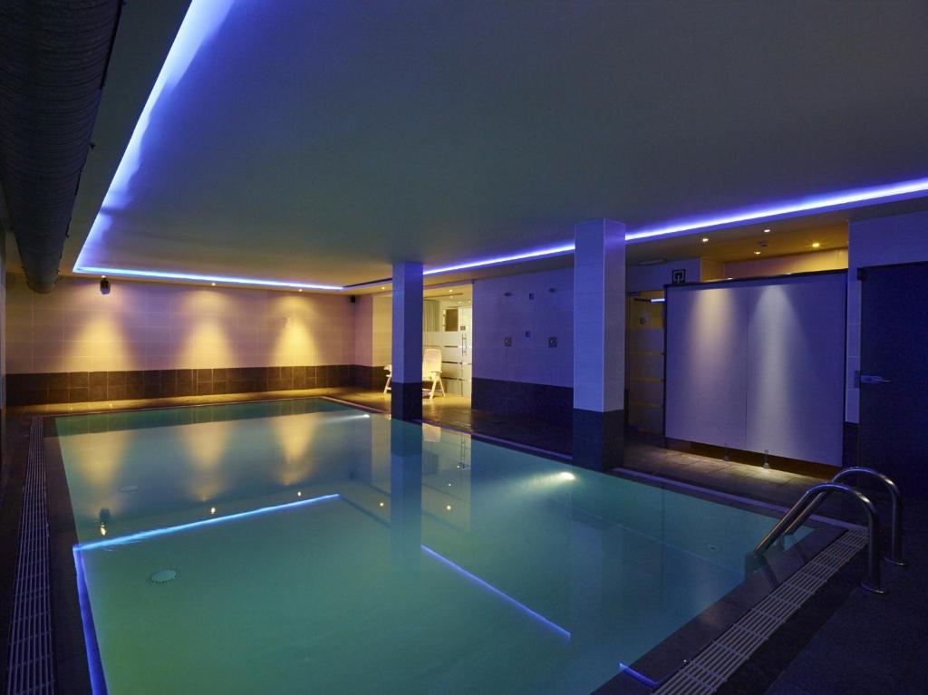 a large swimming pool in a building with a blue lighting at Hotel Europe in Ostend