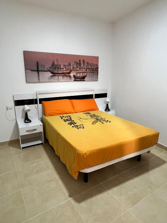 - une chambre dotée d'un lit avec des oreillers orange et un tableau dans l'établissement Casa Da Lella, à Guía de Isora