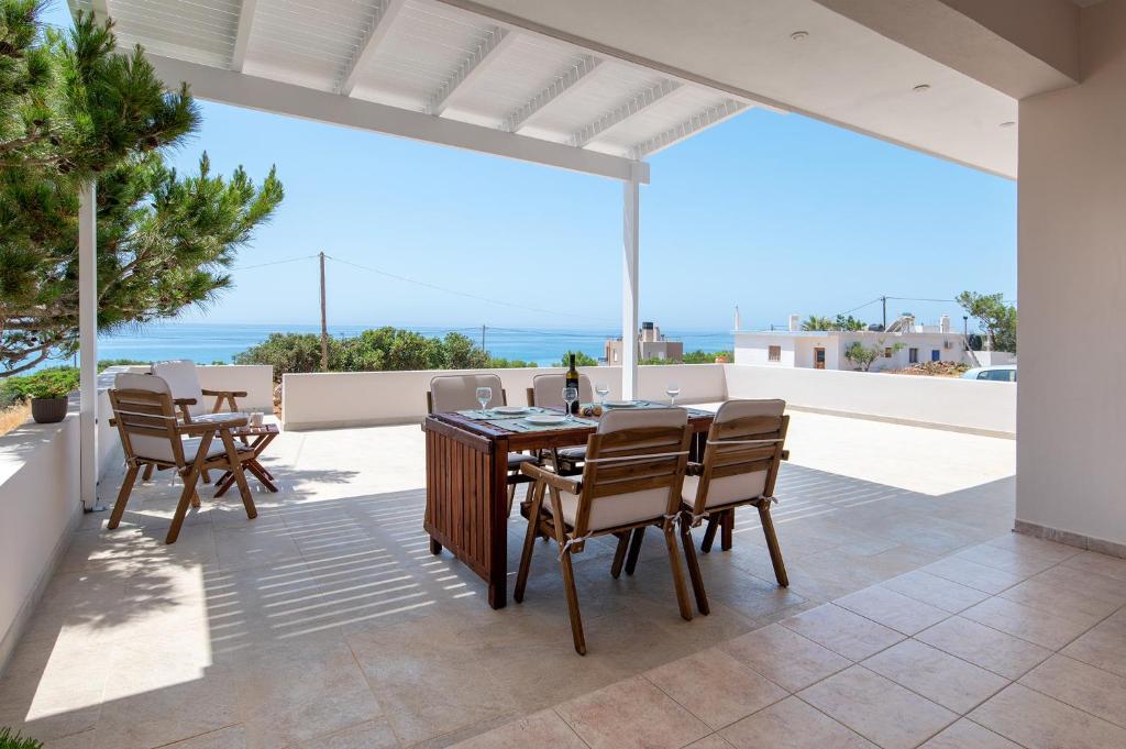 un patio con mesa, sillas y el océano en Sea view Pine house, en Makrí Gialós