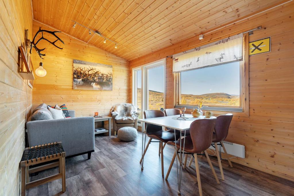 Habitación con mesa, sillas y sofá en Davvi Siida - Reindeer Design Lodge en Kjøllefjord