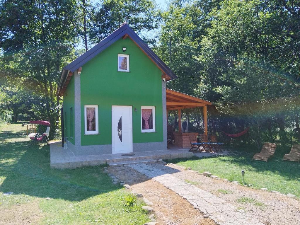 una pequeña casa verde con un porche en un patio en Green House, en Rijeka