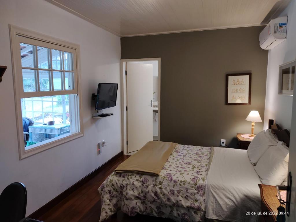 1 dormitorio con cama y ventana en Rancho São Carlos, en Itatiaia