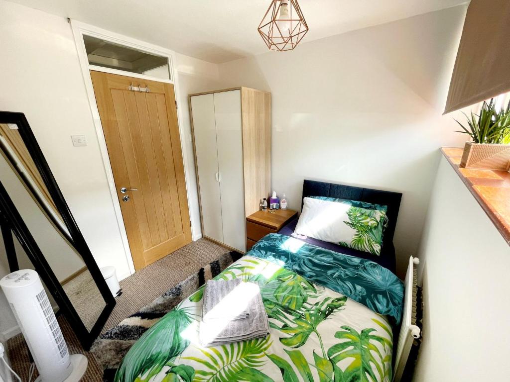 a small bedroom with a bed with a tropical print at 5min Drive to Luton Airport, 2 Train Stations & Motorway - FREE PARKING - LATE CHECK OUT 11AM - Quiet & Peaceful Location with a relaxing Garden - ONLY 25min drive to North LONDON - FREE WIFI in Luton
