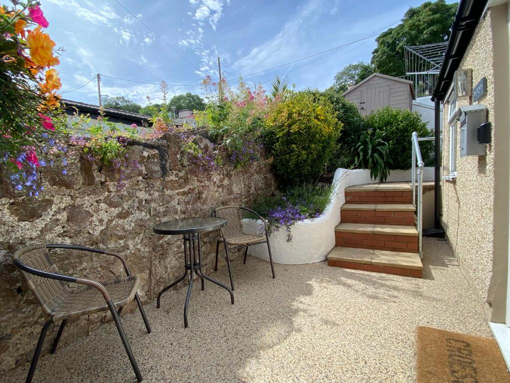 a patio with a table and chairs and a stone wall at Llandudno Boutique style seaside retreat with stunning views in Llandrillo-yn-Rhôs