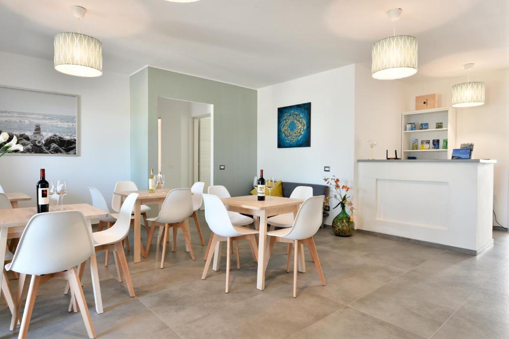 una sala da pranzo con sedie bianche e tavoli in legno di Prima Luna a Bari Sardo