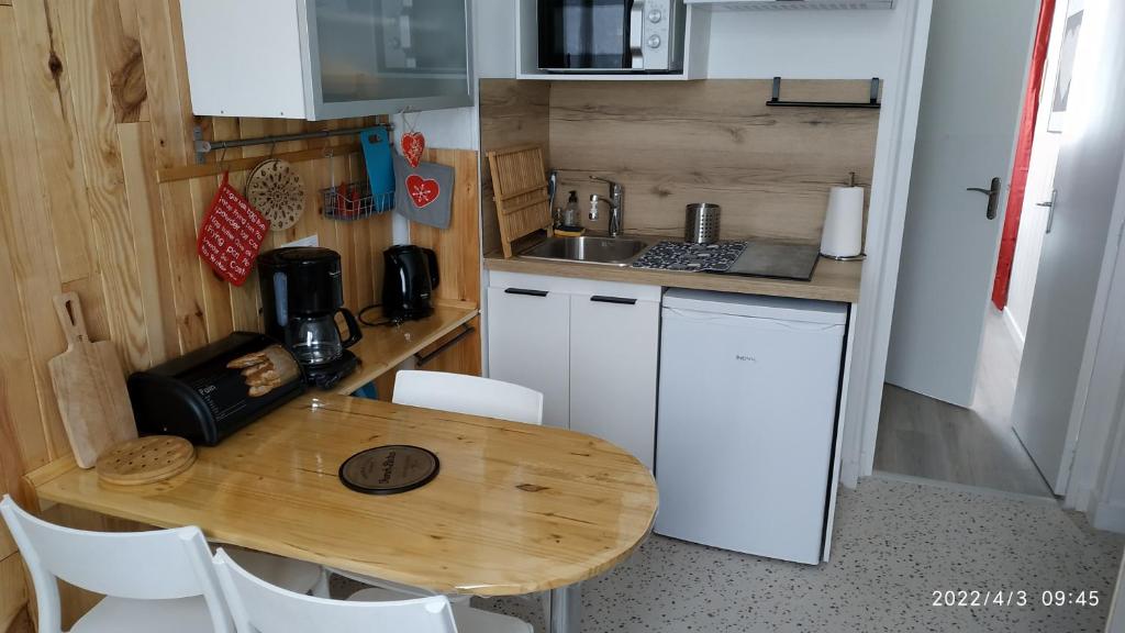 uma pequena cozinha com uma mesa de madeira e uma bancada em Logement refait à neuf - Résidence - Chez Christian em La Bourboule