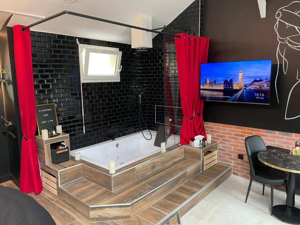 Cette chambre dispose d'une baignoire et de rideaux rouges. dans l'établissement Luxe and Spa, à Condé-Sainte-Libiaire