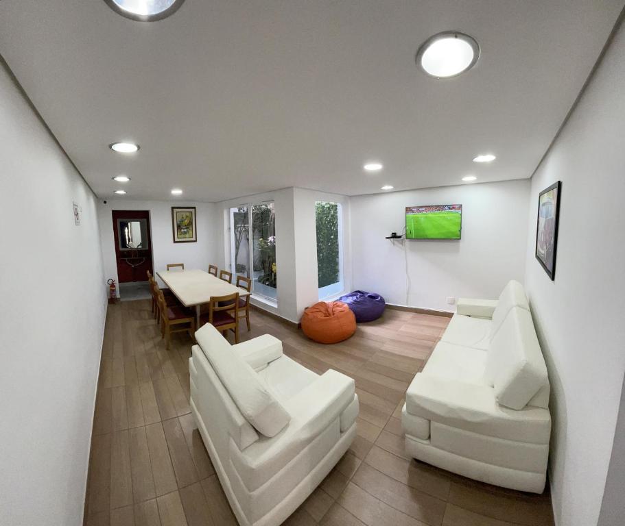 a living room with two white chairs and a table at Jardins Village Hostel - Jardim Paulista in São Paulo