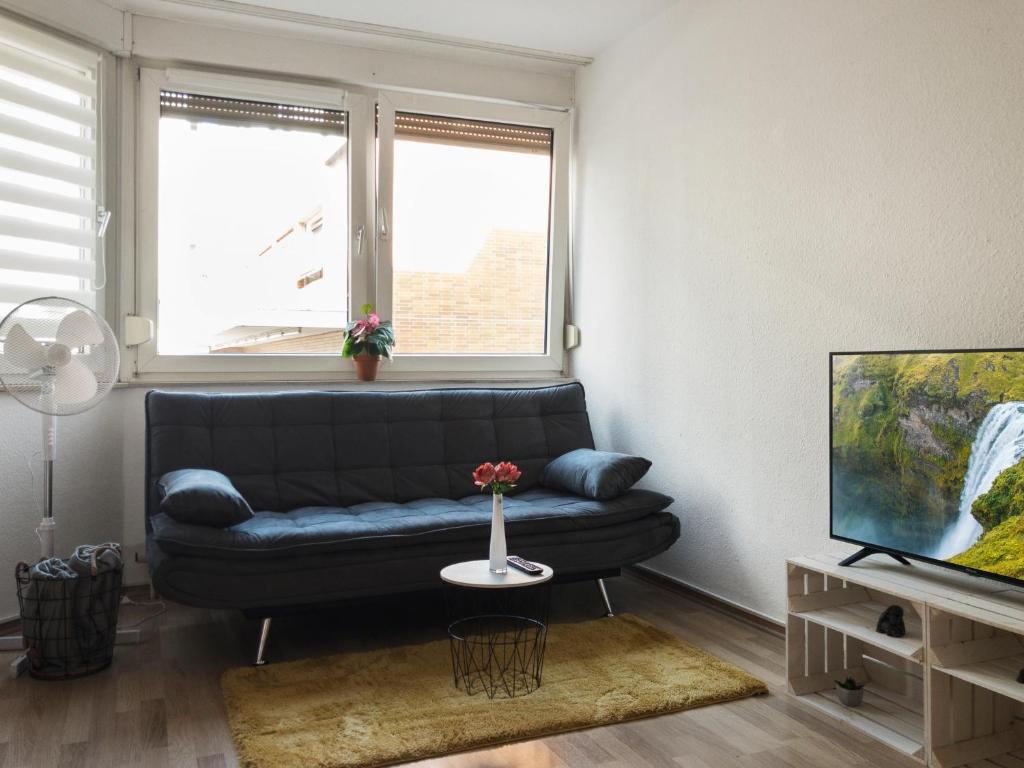 a living room with a black couch and a tv at Helles Studio in Innenstadt mit Netflix in Mannheim