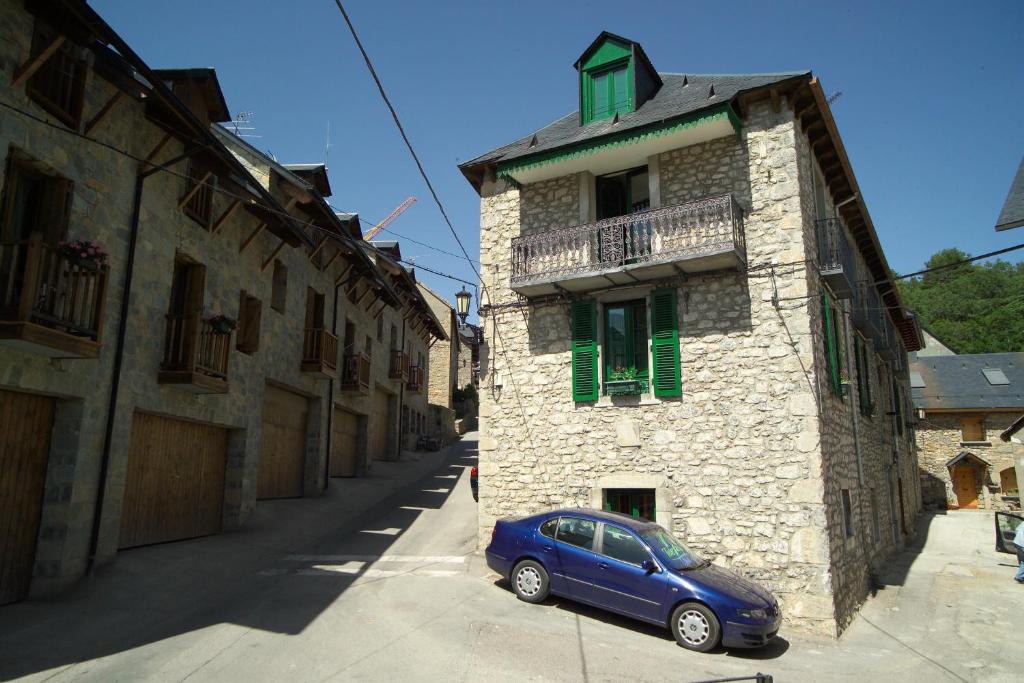 une petite voiture bleue garée devant un bâtiment dans l'établissement Apartamentos Codallos, à Tramacastilla de Tena