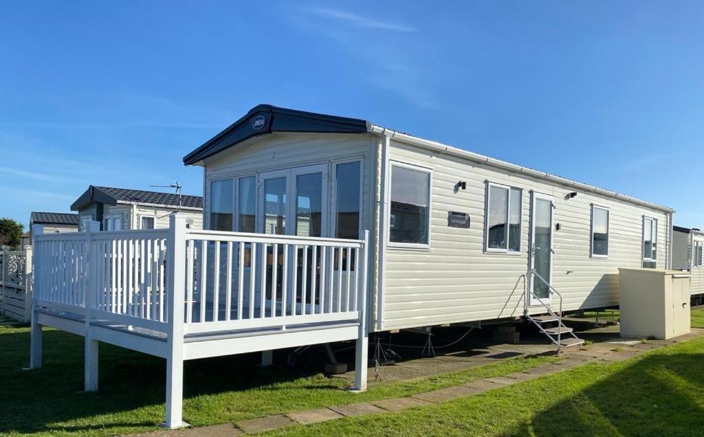 un mobile home avec une terrasse couverte et une clôture dans l'établissement holidayhome-romneysands holiday park, à Littlestone-on-Sea