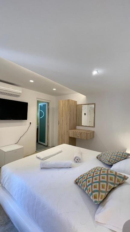 a bedroom with a large white bed and a television at Rida Village Ksamil Island in Ksamil