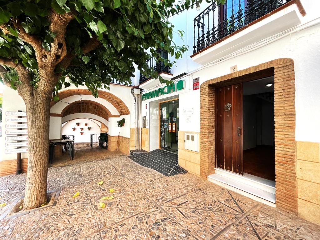 a building with a tree in front of a sidewalk at Casa de la Plaza in Fondón