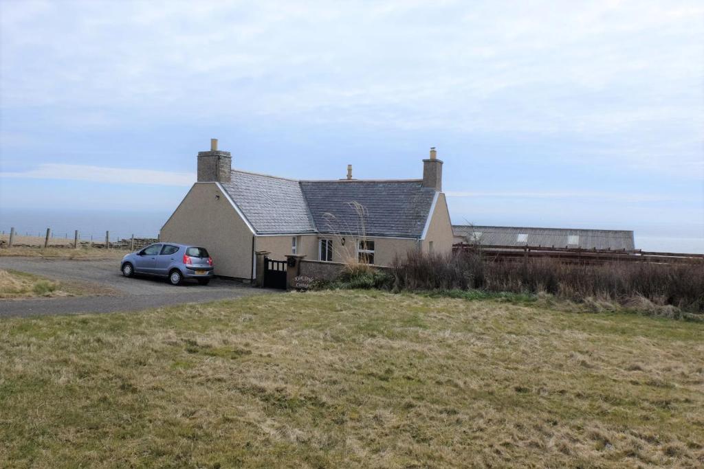 a house with a car parked in front of it at Fabulous location with sea and castle view - NC500 in Keiss