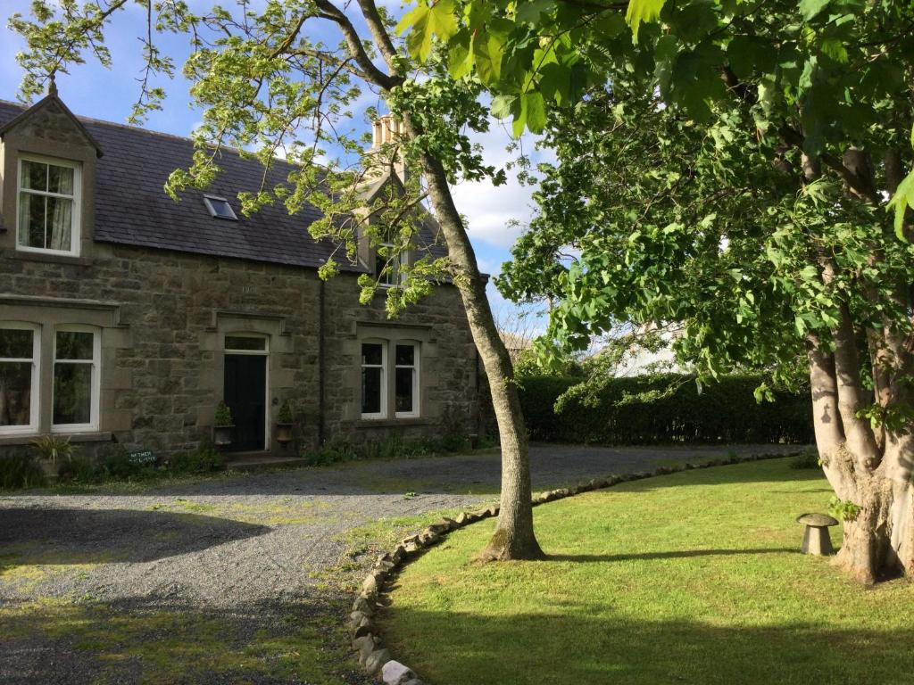 班夫的住宿－Nether Dallachy Farmhouse，前面有树木的石头房子