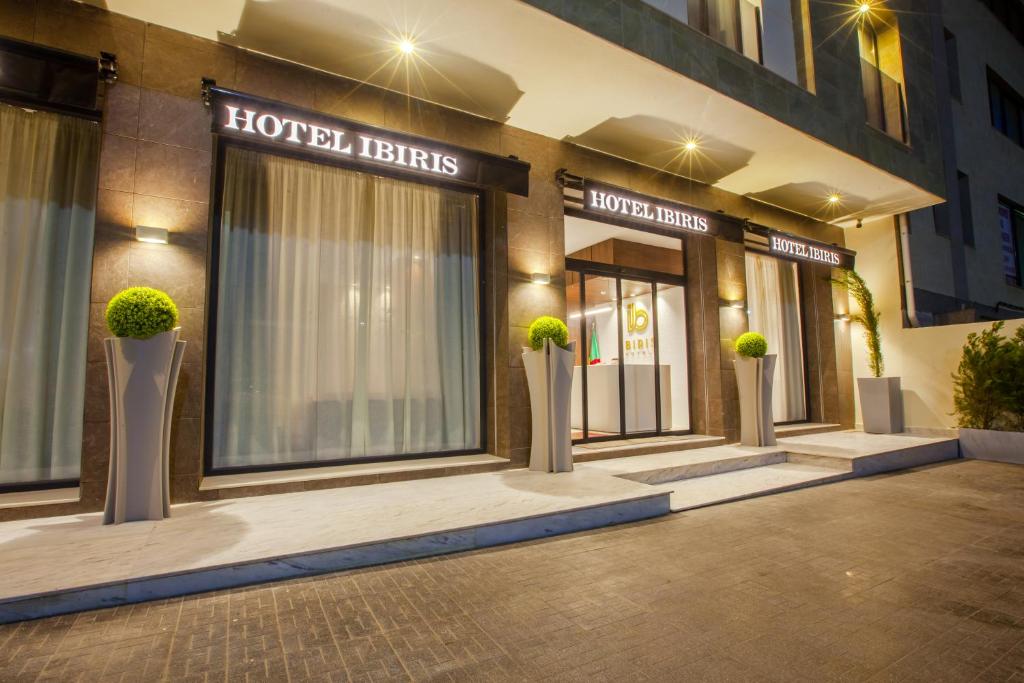 a hotel with potted plants in front of a building at IBIRIS in Oran