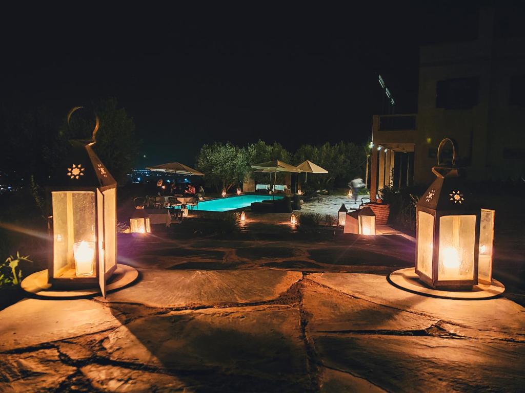 a patio with lights and a swimming pool at night at ourika oufla in Ourika