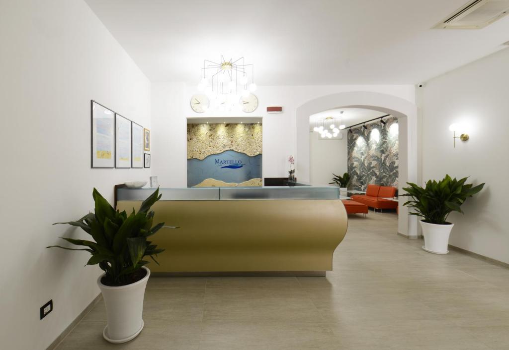 a lobby with a reception desk and potted plants at Hotel Martello in Lampedusa