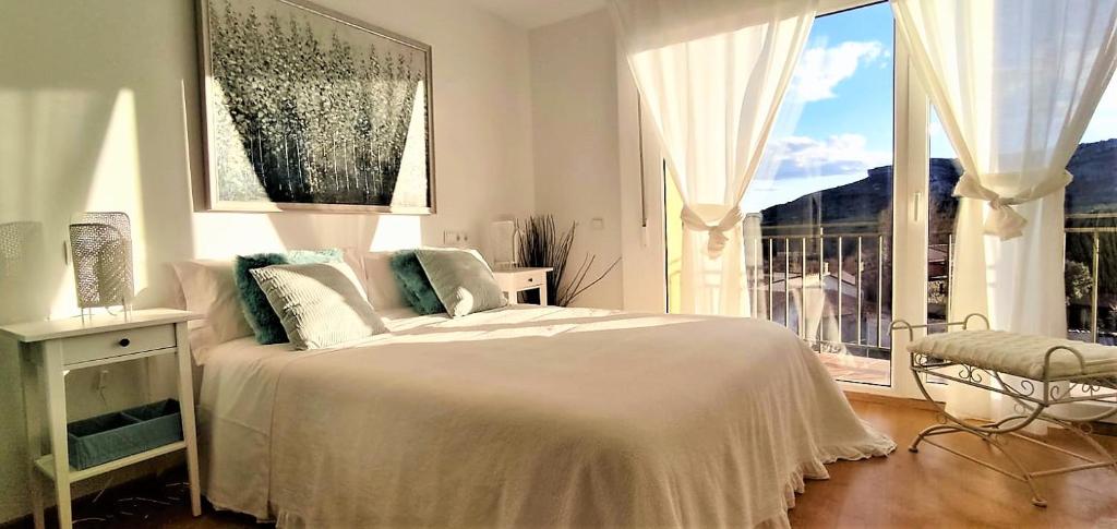 a white bedroom with a bed and a large window at LA CASA DE FUENTETOBA in Fuentetoba