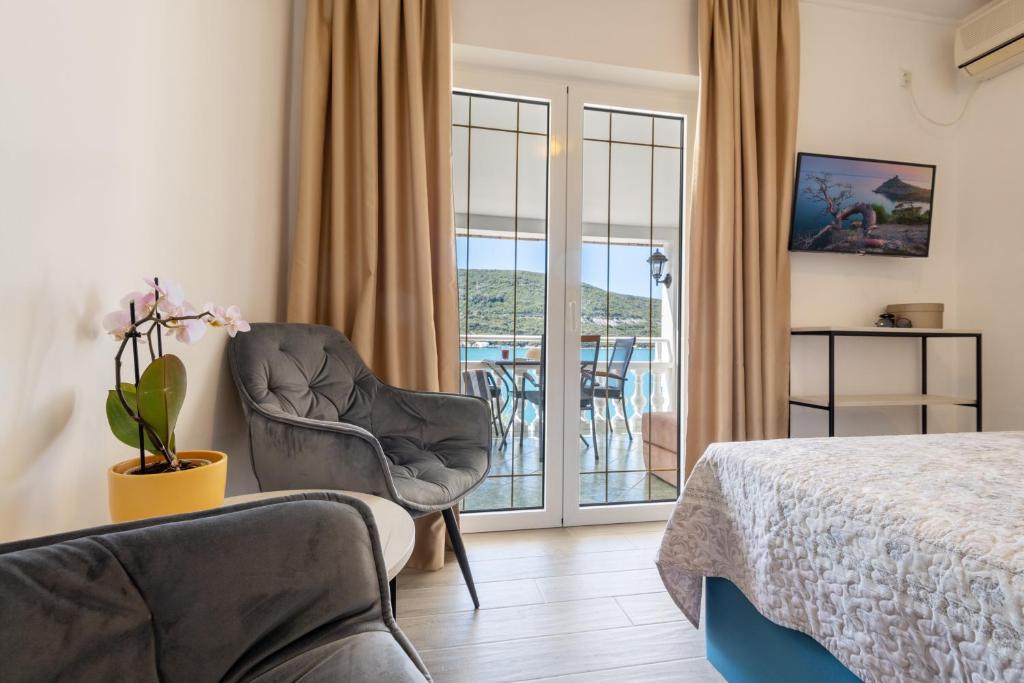 a bedroom with a bed and a chair and a balcony at Apartments Sentic in Neum