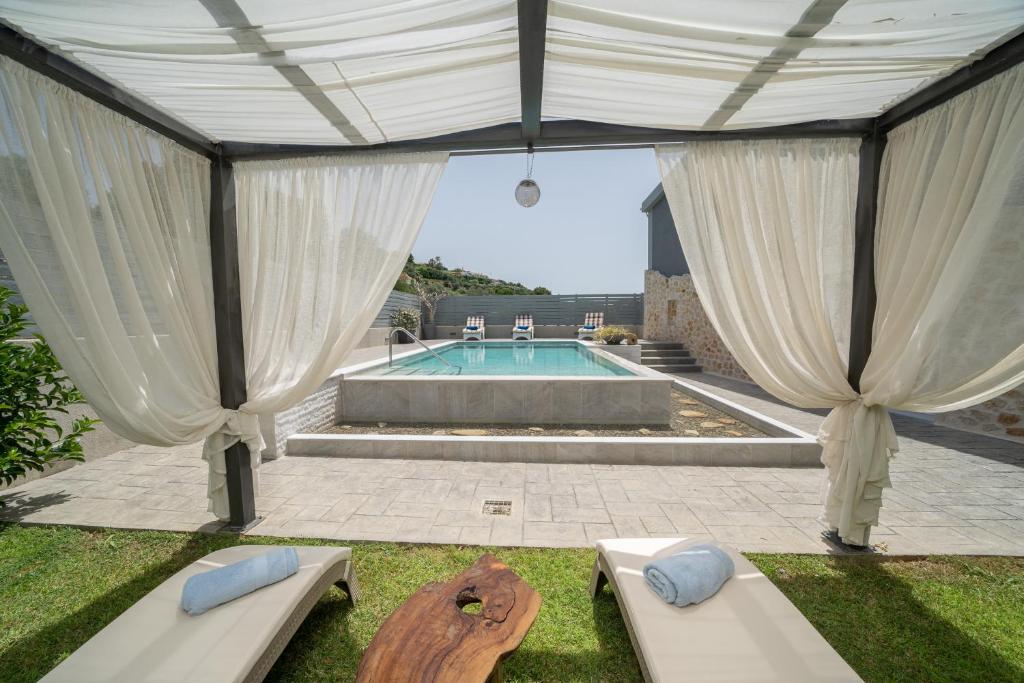 a pavilion with white curtains and a swimming pool at Popi's Villa in Svoronata