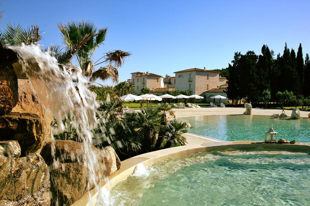 a swimming pool with a water fountain in a resort at Tartheshotel in Guspini