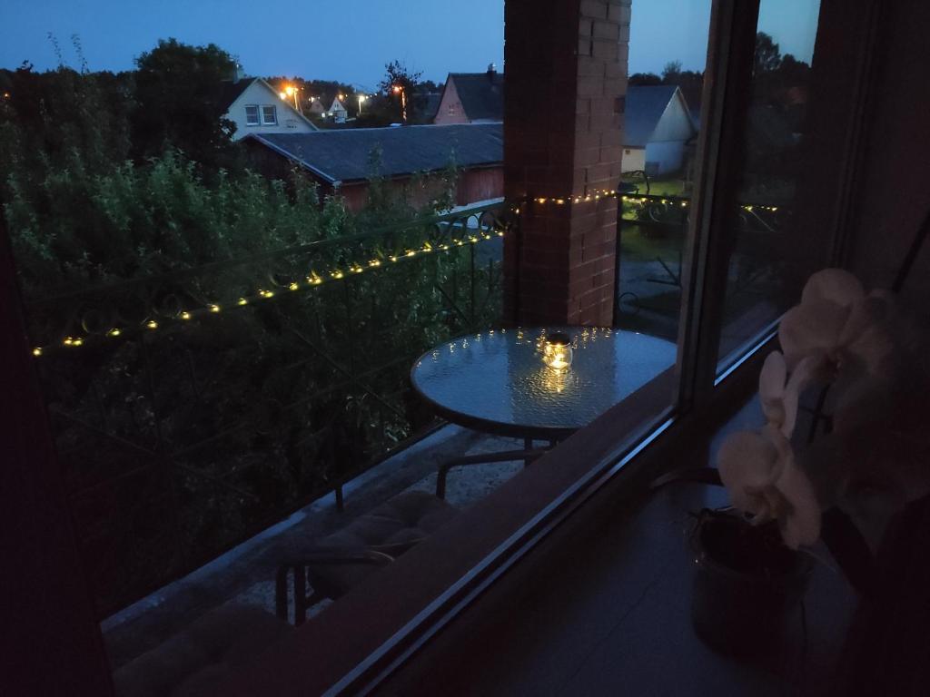 a room with a table on a balcony at night at Spacious & Cozy Apartment with Forest View in Zapyškis