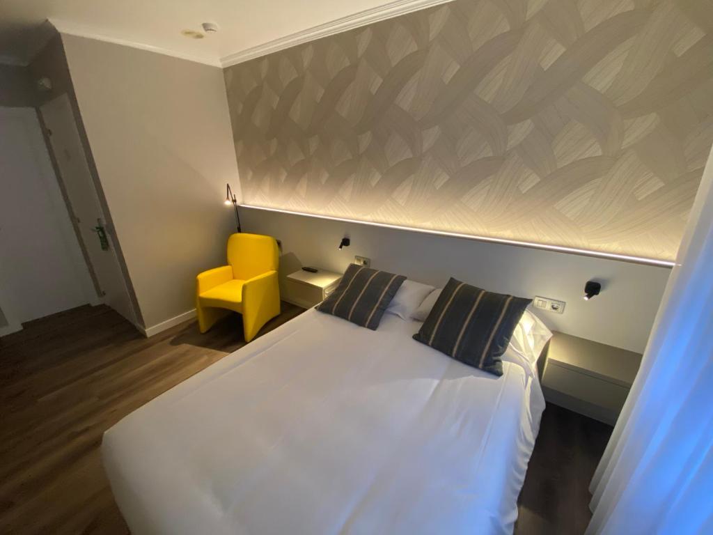 a bedroom with a white bed and a yellow chair at Villa Alta in Villalba