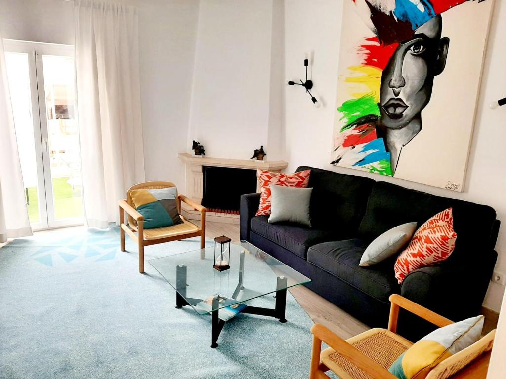 a living room with a black couch and a painting at Alojamento local "CASA BRANCA" in Albufeira