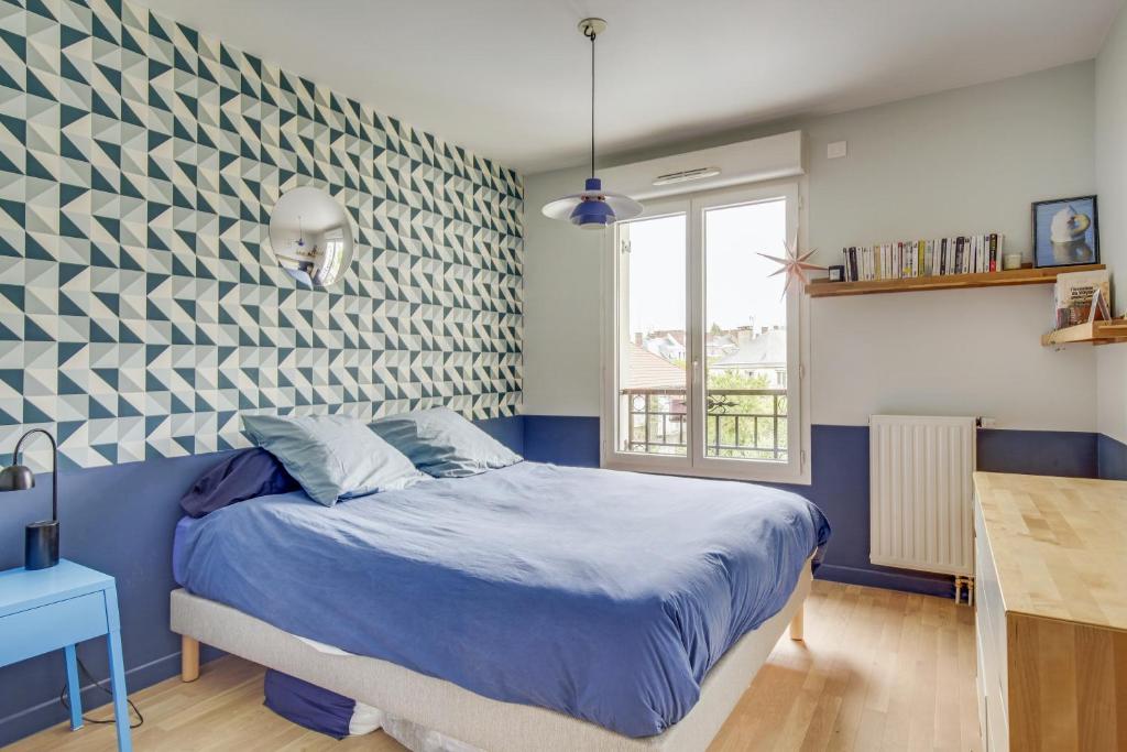 a bedroom with a blue bed and a wall at Le Saint Cyr in Saint-Cyr-lʼÉcole