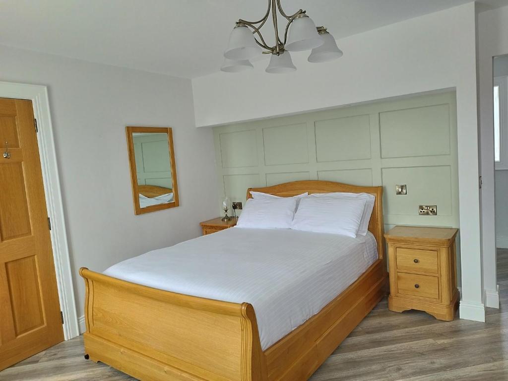 a bedroom with a large bed with white sheets and a mirror at Biddy Ban’s in Carnmalin
