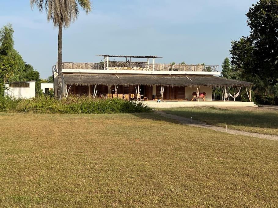 ein Gebäude mit einer Palme vor einem Hof in der Unterkunft Grande maison en bordure de plage in Palmarin