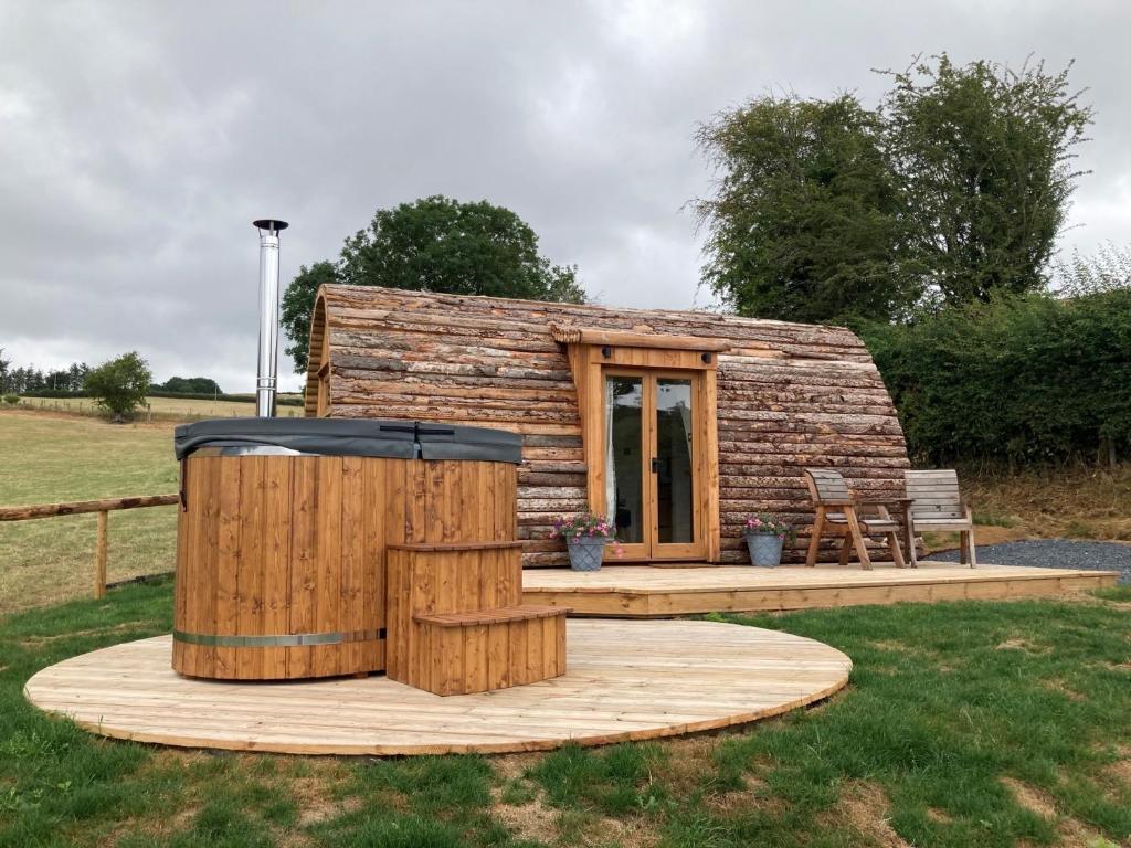 um chalé de madeira com uma banheira de hidromassagem no quintal em Delor - Bryntalch Glamping Pods em Montgomery